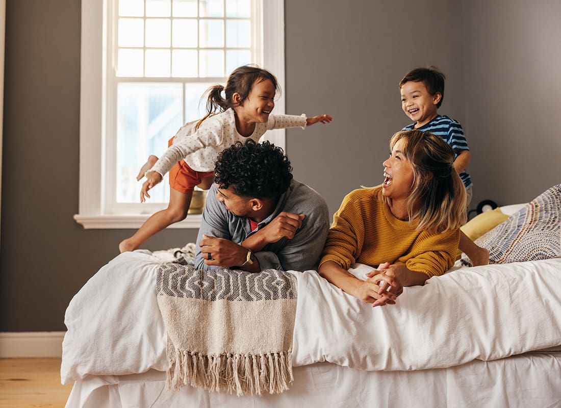 Contact - Cheerful Diverse Young Family with a Son and Daughter Having Fun Playing on the Bed at Home