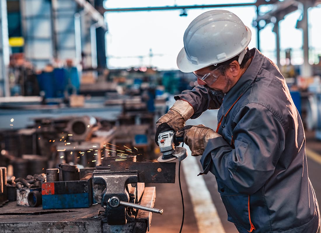 Insurance by Industry - View of a Male Employee Grinding Metal Inside a Manufacturing Facility